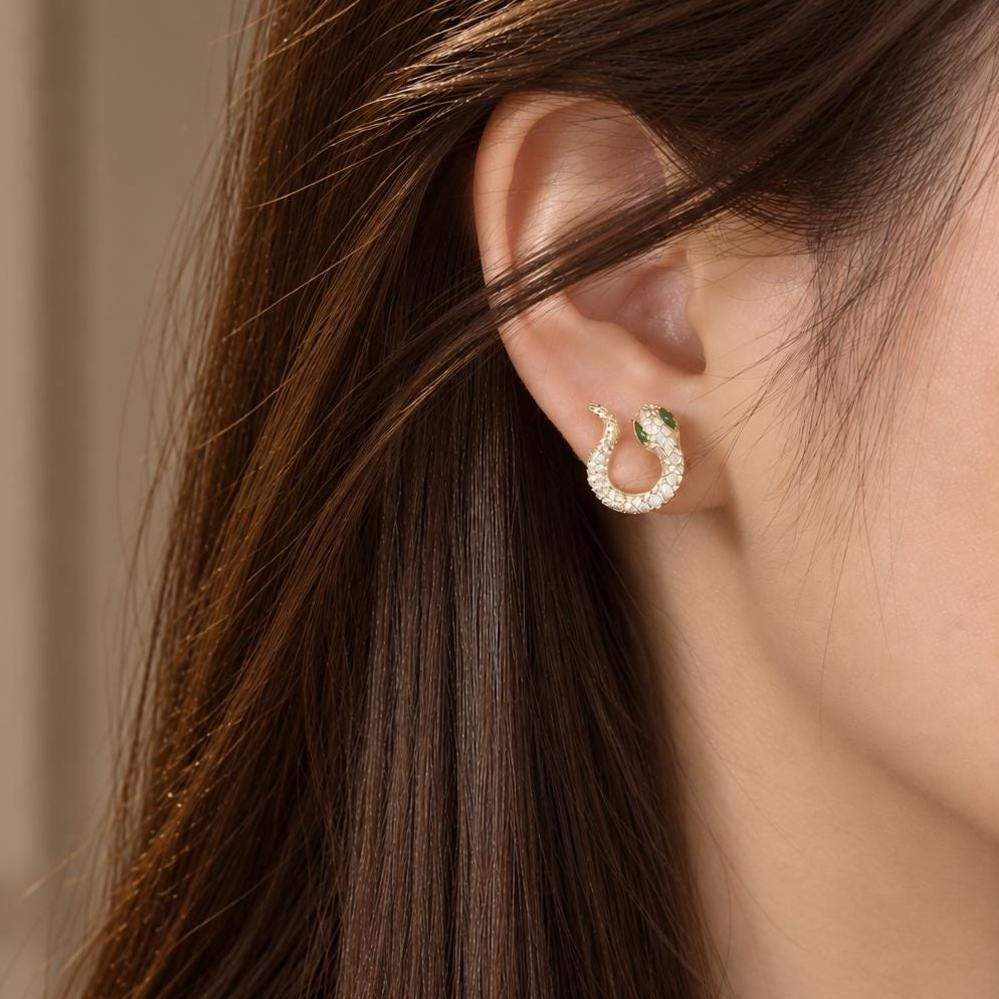 Gold snake stud earring worn on the ear